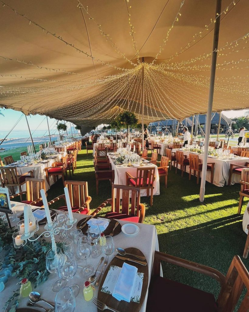 Carpa con mesas redondas, mantelería clara y sillas decoradas en rojo