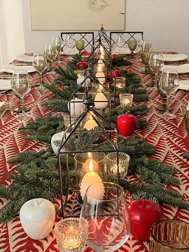 Mesa navideña larga decorada con velas y ramas verdes