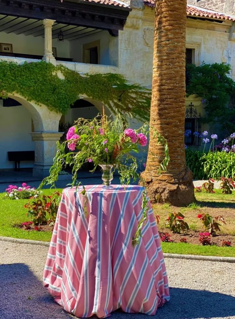 Mesa auxiliar decorada en jardín con mantel a rayas y florero