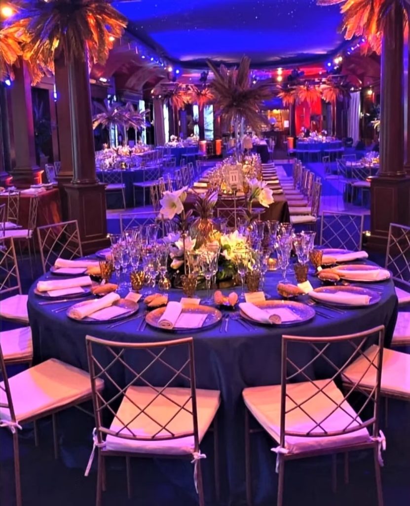 Montaje elegante en salón con iluminación azul y mesas circulares decoradas